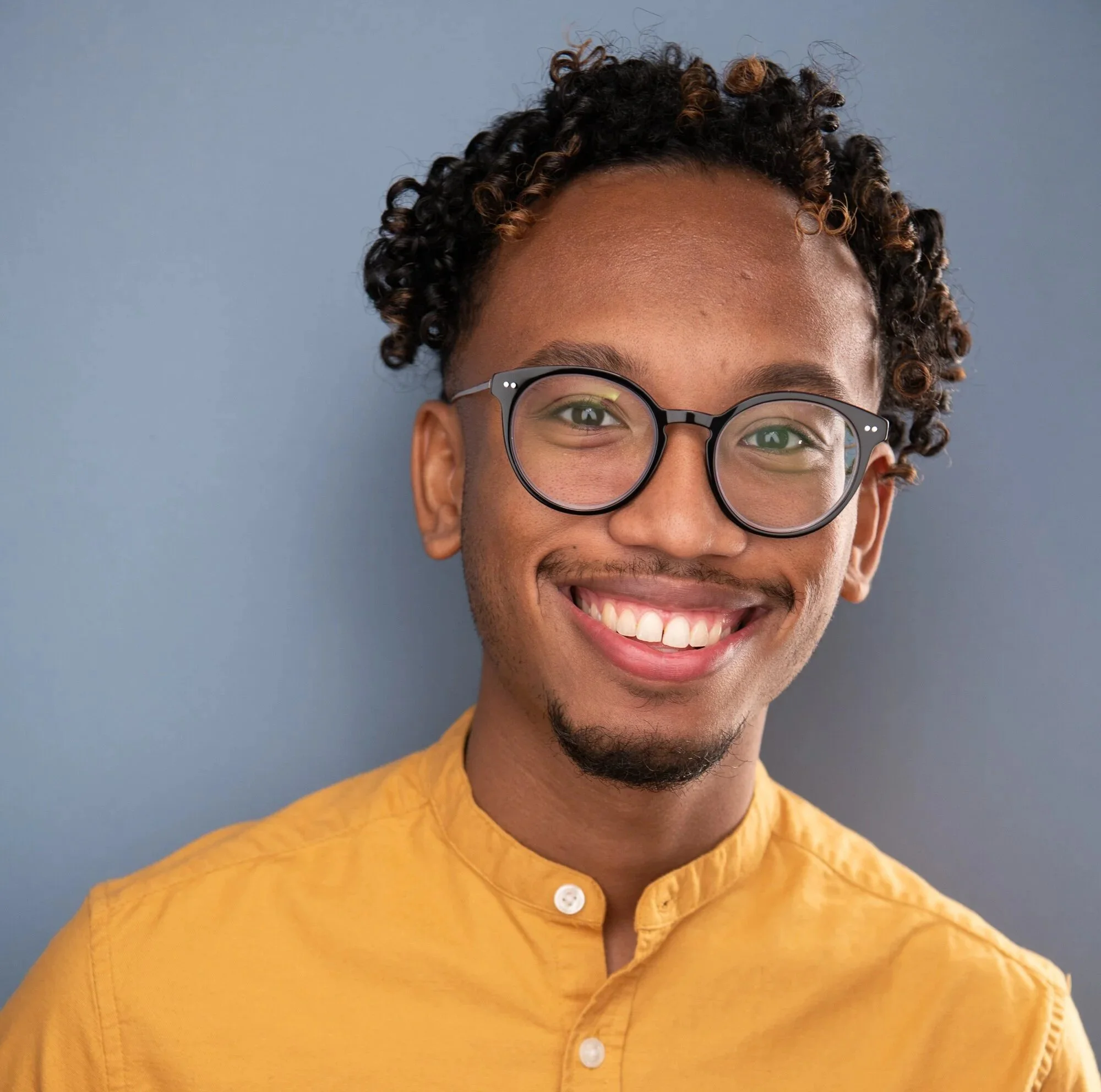 Headshot of Patrick B. Phillips in a mustard shirt